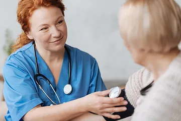 Smiling nurse taking a lady's vital signs